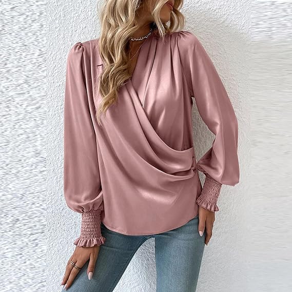Blusa rosa satinata con maniche lunghe a sbuffo, scollo a V drappeggiato, indossata con jeans. Elegante moda femminile, look casual chic.