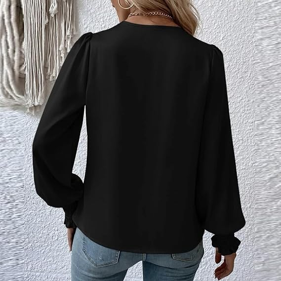 Donna con camicetta nera a maniche lunghe, vista posteriore, indossa jeans. Sfondo con parete bianca e decorazione tessile. Moda casual elegante.