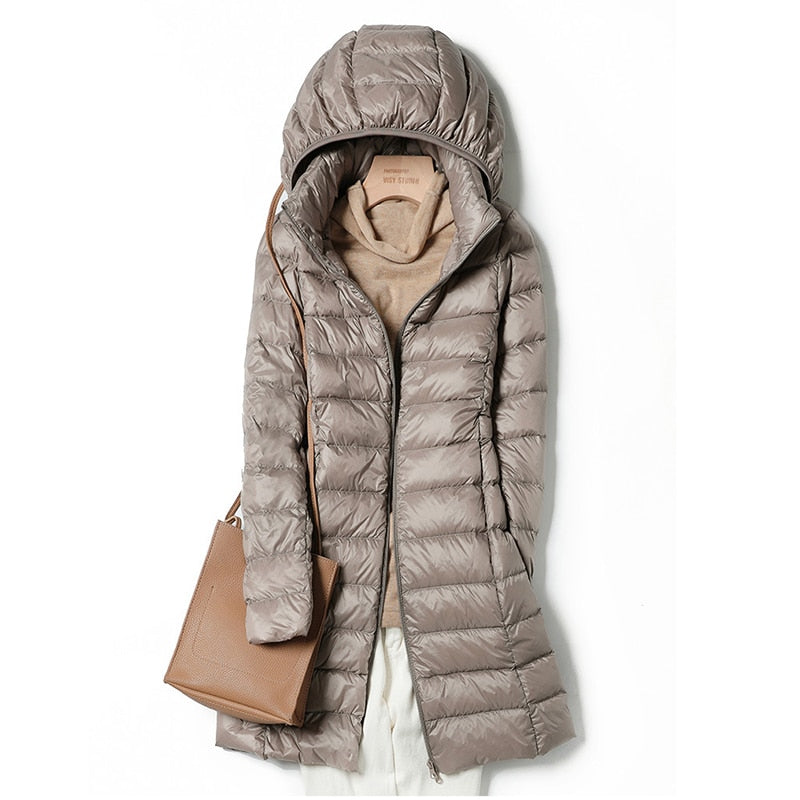 Giacca invernale imbottita beige con cappuccio, abbinata a maglione beige e borsa a tracolla marrone. Moda donna, abbigliamento caldo e casual.