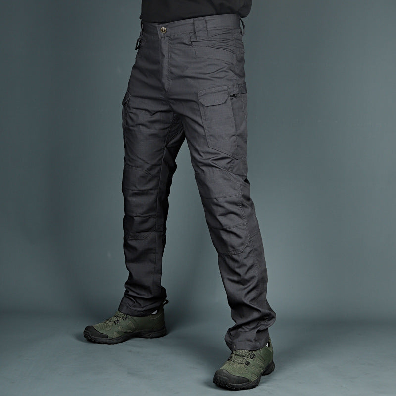 Pantaloni tattici grigi con tasche multiple, indossati con scarpe da trekking verdi. Abbigliamento outdoor resistente e funzionale per escursioni.