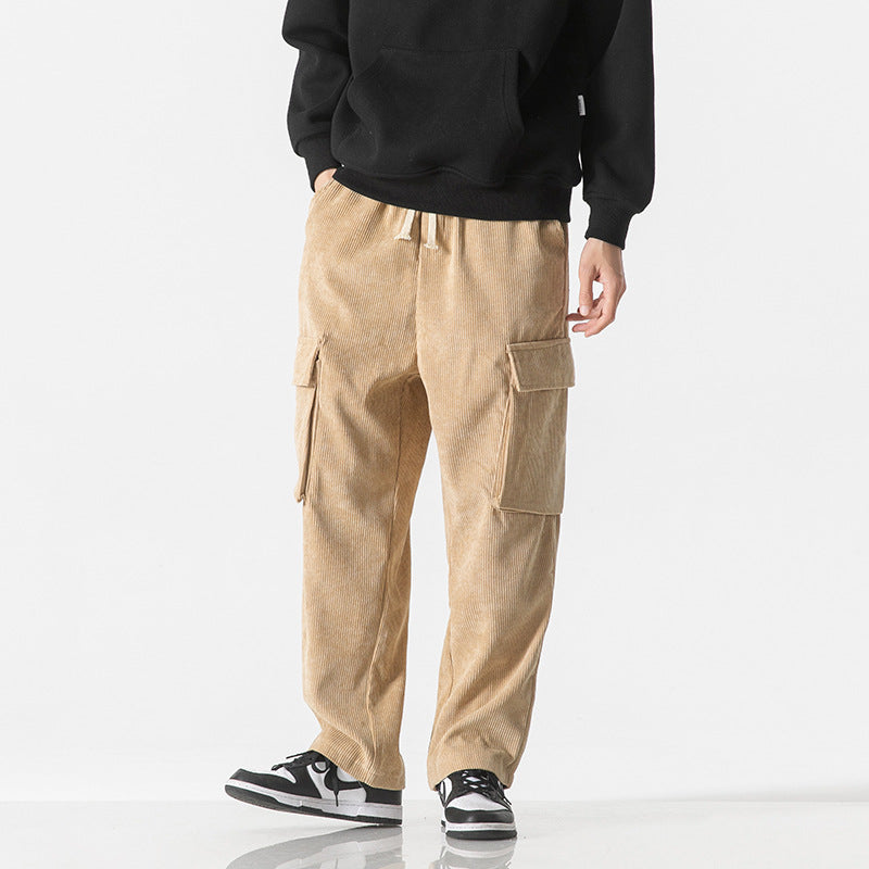 Pantaloni cargo beige in velluto a coste, tasche laterali, indossati con felpa nera e sneakers bianche e nere. Moda casual uomo autunno inverno.