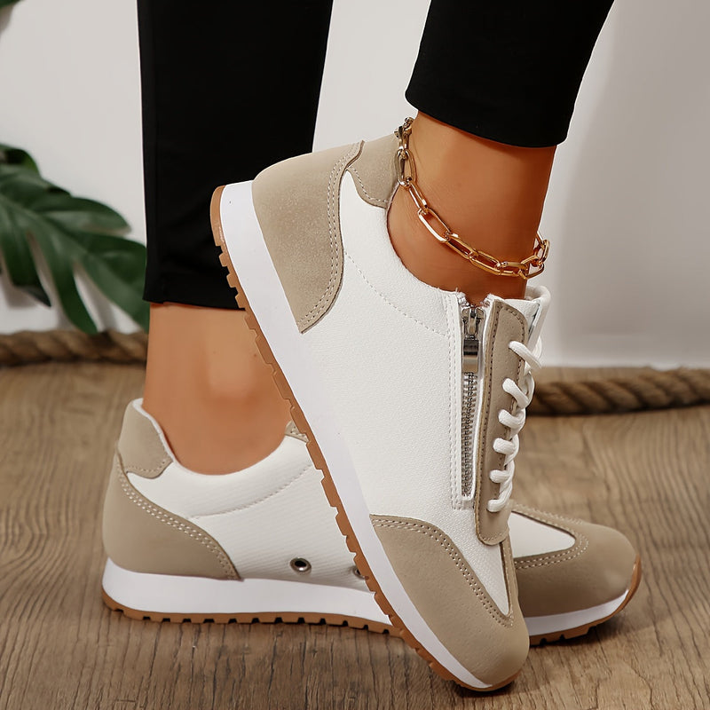 Scarpe da ginnastica bianche e beige con cerniera, suola in gomma antiscivolo, indossate su pavimento in legno. Accessorio cavigliera dorata.