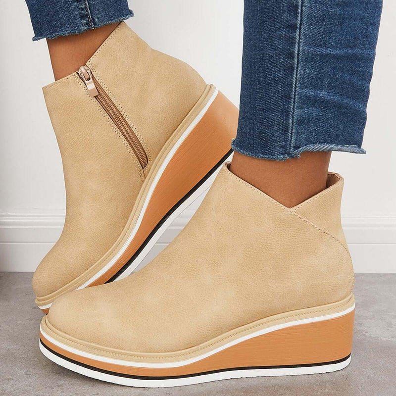Stivaletti beige con zeppa alta, cerniera laterale, suola bianca e marrone, indossati con jeans. Scarpe moda donna autunno inverno.