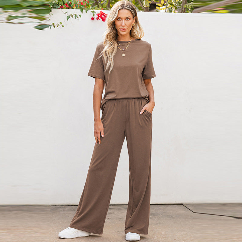 Donna in tuta marrone casual, con pantaloni larghi e maglietta a maniche corte, posa all'aperto. Stile moda donna, abbigliamento comodo.