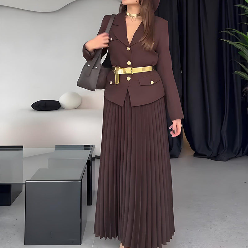 Donna in abito marrone elegante con cintura dorata, borsa nera, in un salotto moderno. Moda autunnale, stile sofisticato, tendenze 2023.