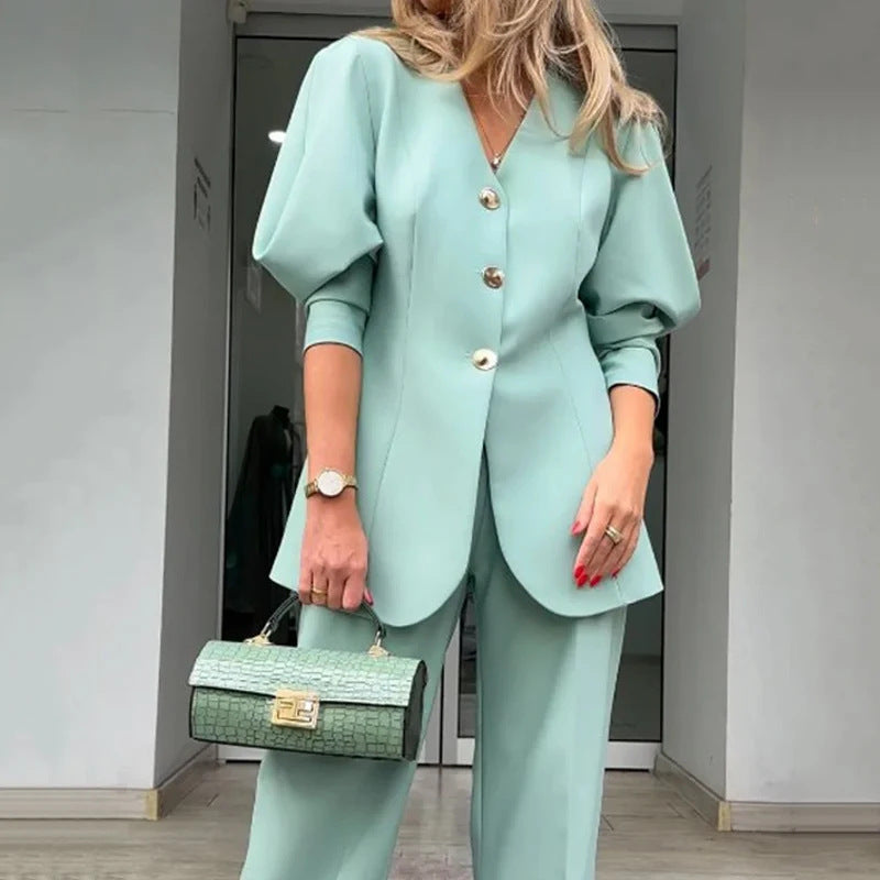 Donna in elegante completo verde menta con giacca a maniche a sbuffo e pantaloni abbinati, borsa a mano verde, moda femminile contemporanea.