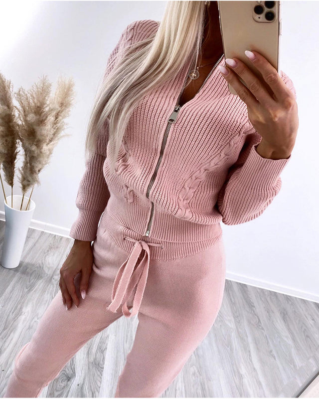 Donna in tuta rosa a maglia con zip, selfie allo specchio. Moda autunnale, abbigliamento casual elegante, pavimento in legno, piante decorative sullo sfondo.