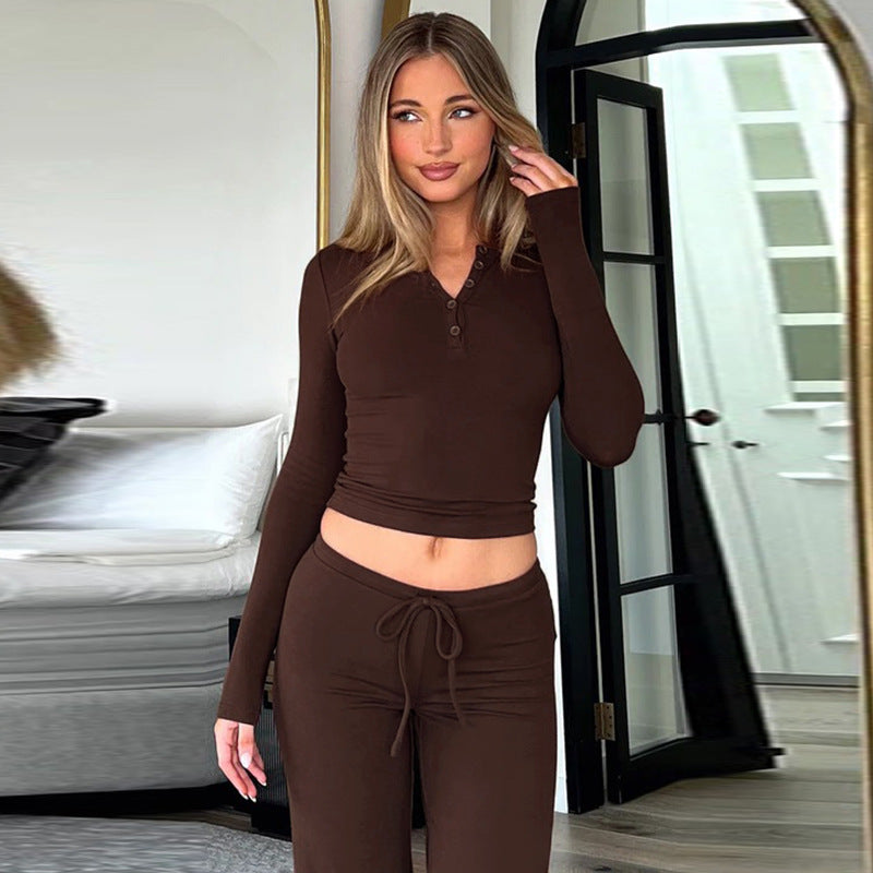 Donna in abbigliamento lounge marrone, posa in una stanza moderna con specchio e porta nera. Stile casual, moda autunnale, comfort domestico.
