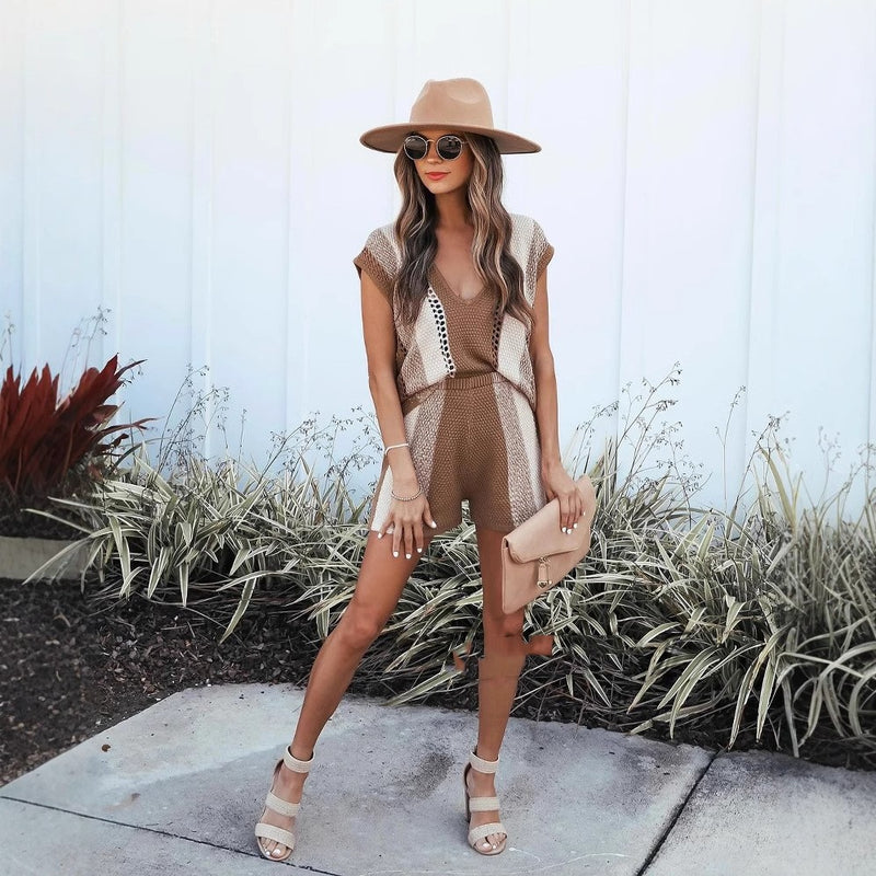 Donna alla moda con cappello beige, occhiali da sole e tuta marrone, posa all'aperto. Stile estivo chic, accessori eleganti, look casual.