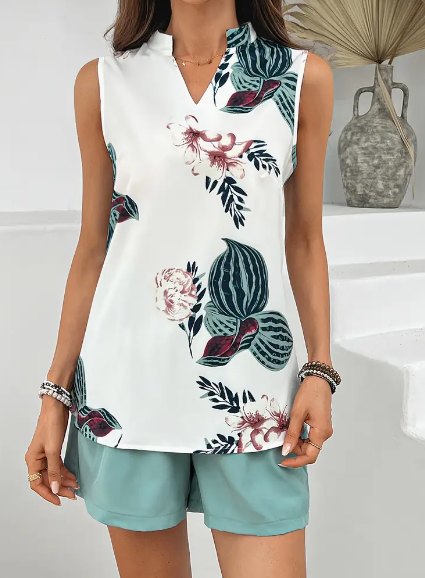 Donna con top senza maniche bianco a fiori e pantaloncini verde acqua, sfondo minimalista. Moda estiva, abbigliamento casual elegante.