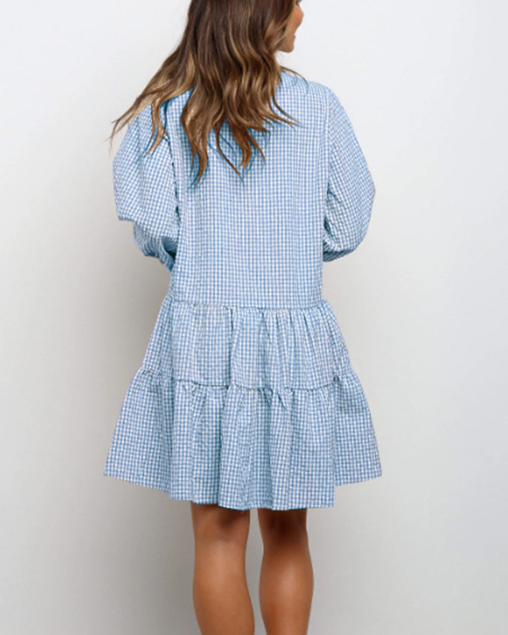 Donna con abito a quadri blu e bianco, maniche lunghe e gonna a balze. Moda femminile casual, stile estivo, abbigliamento leggero.