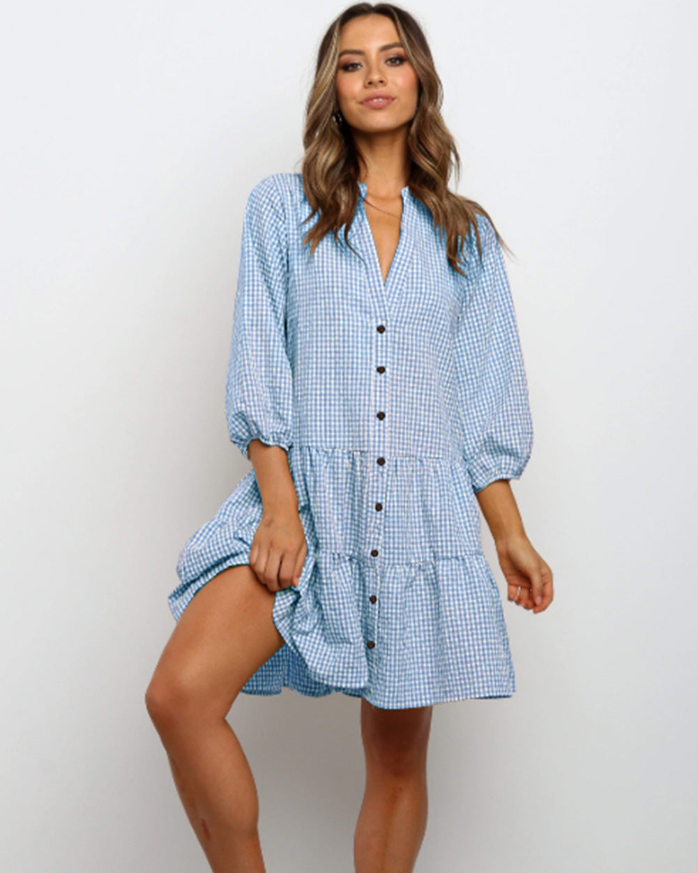 Donna con abito a quadretti blu e bianco, maniche lunghe, bottoni frontali. Moda casual femminile, stile estivo, abbigliamento trendy.