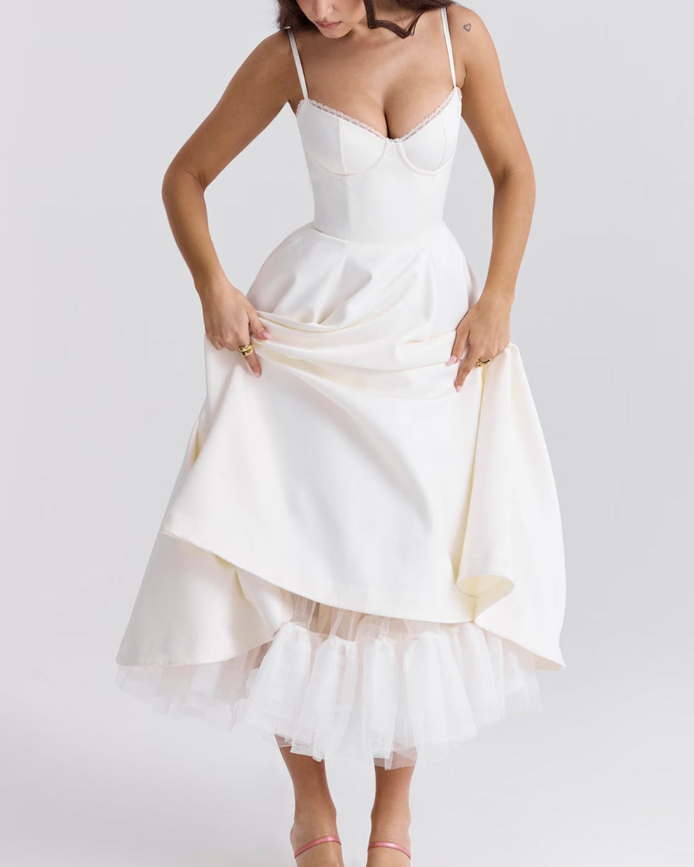 Donna in abito bianco elegante con corpetto aderente e gonna a strati, posa su sfondo neutro. Moda femminile, abbigliamento da cerimonia.