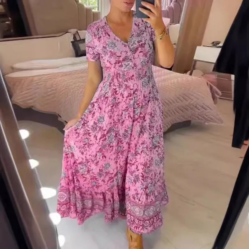Donna in abito lungo floreale rosa, scatta selfie in camera da letto moderna. Moda estiva, abbigliamento femminile elegante, tendenze 2023.