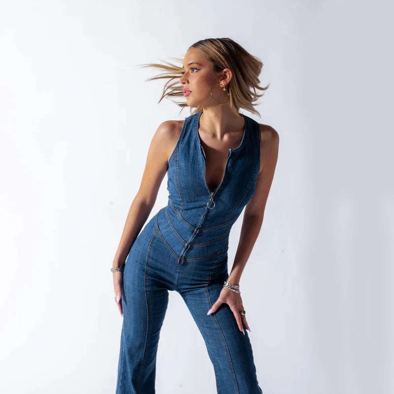 Donna in tuta di jeans blu, con zip frontale, posa dinamica su sfondo bianco. Moda femminile, abbigliamento casual, stile contemporaneo.