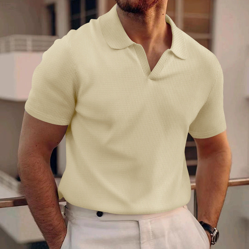 Uomo con polo beige a maniche corte, in piedi su un balcone. Moda estiva maschile, abbigliamento casual elegante, tendenze moda uomo 2023.