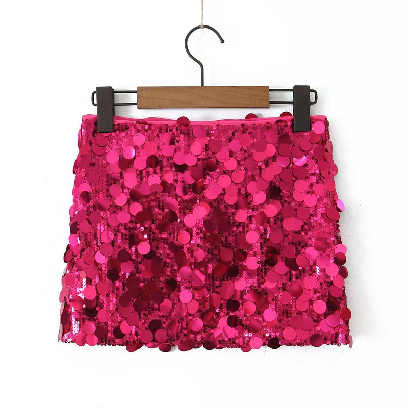 Gonna mini rosa con paillettes scintillanti, appesa su gruccia di legno. Moda femminile, abbigliamento da festa, stile glamour.