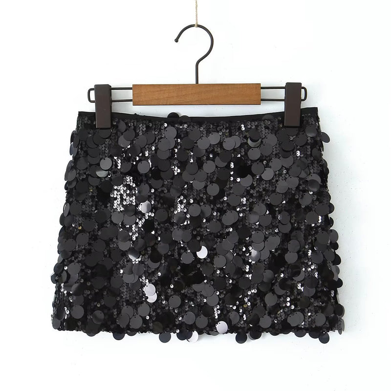 Gonna corta nera con paillettes scintillanti, appesa su gruccia di legno. Moda elegante, abbigliamento da festa, stile glamour.