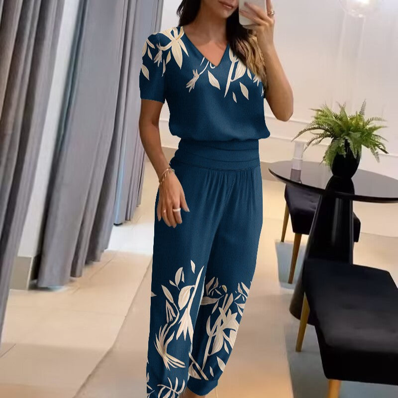 Donna in tuta blu con motivi floreali bianchi, scatta un selfie in un ambiente moderno. Abbigliamento elegante, moda femminile, stile casual chic.