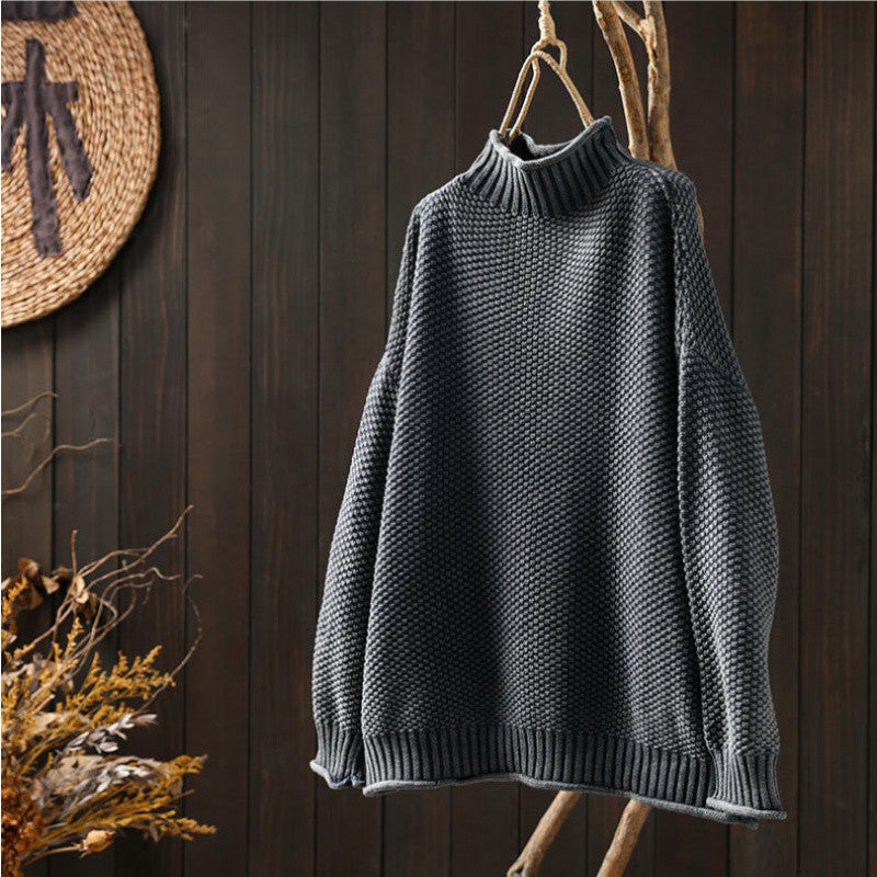 Maglione grigio a collo alto in maglia spessa appeso su sfondo di legno scuro, moda autunno inverno, abbigliamento caldo e accogliente.