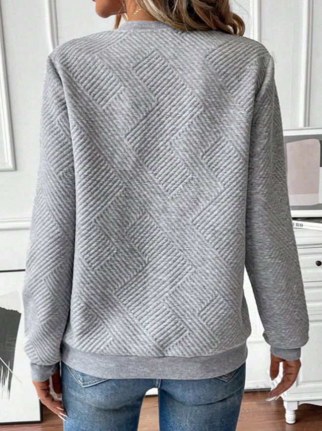 Donna con maglione grigio trapuntato a zigzag, vista posteriore. Moda casual autunnale, tessuto morbido, design moderno. Jeans blu abbinati.