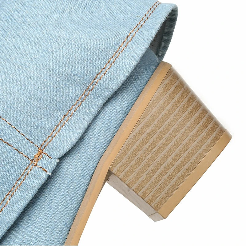 Primo piano di un tacco quadrato in legno su stivale in denim azzurro, cuciture a vista. Scarpe moda donna, stile casual chic.