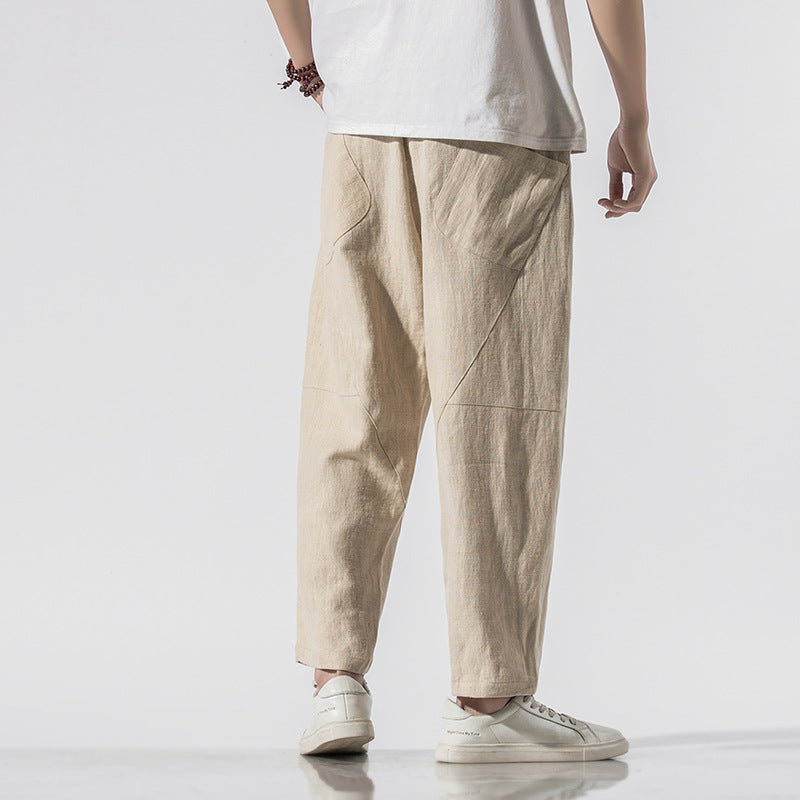 Pantaloni larghi beige in lino, stile casual, indossati con scarpe bianche e maglietta bianca. Moda uomo, abbigliamento estivo, comfort.