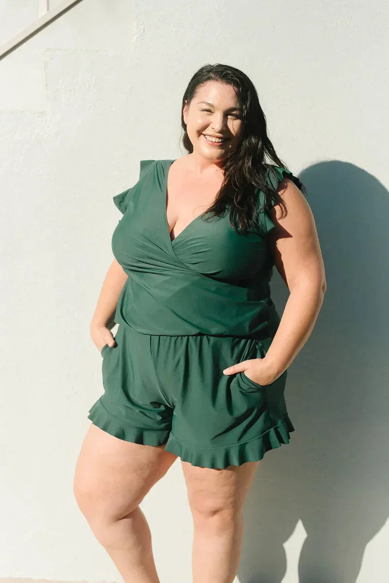 Donna sorridente in tuta verde, moda taglie forti, posa all'aperto. Abbigliamento estivo elegante, stile casual, comfort e tendenza.