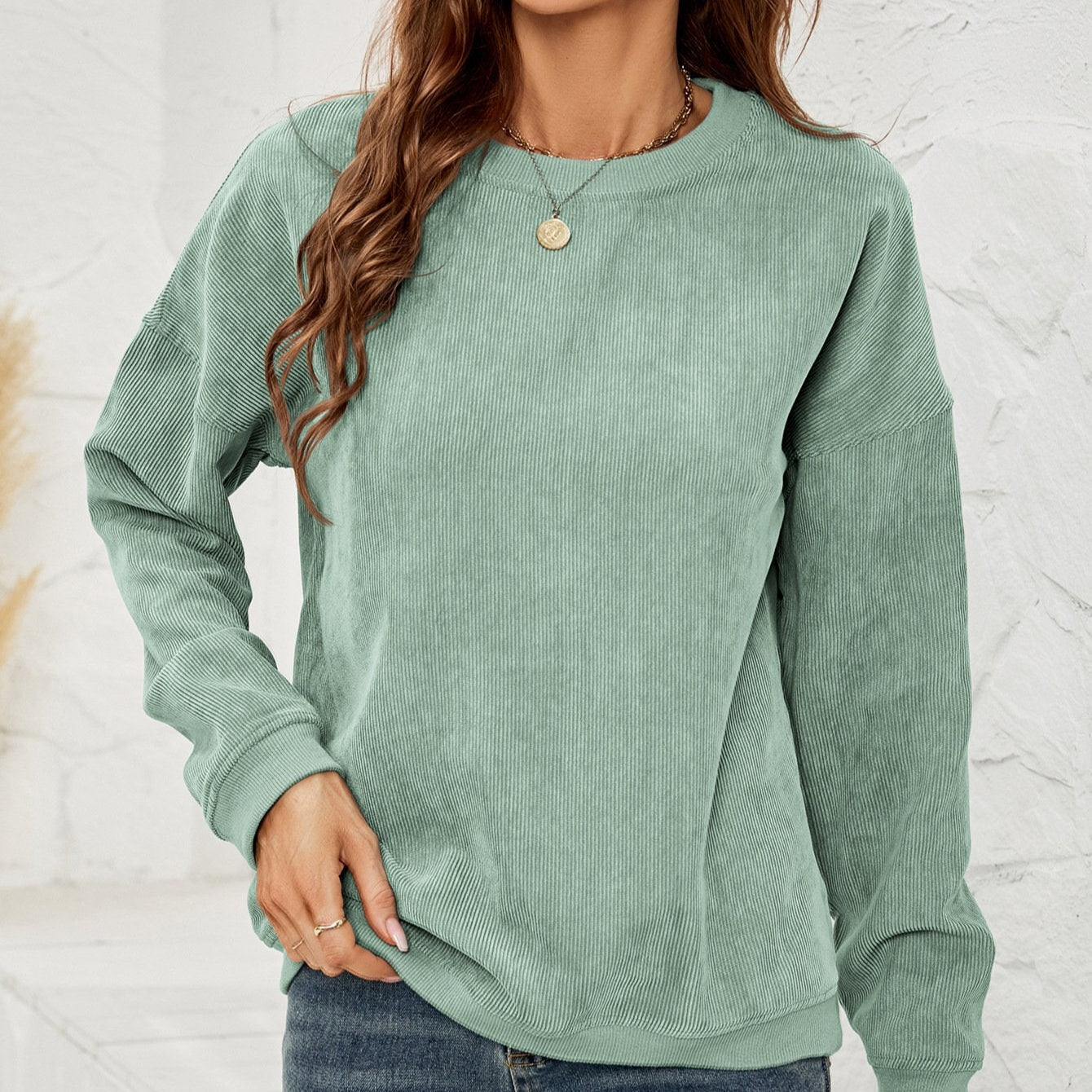 Donna con maglione verde menta in velluto a coste, collana dorata e jeans. Moda casual autunnale, abbigliamento femminile trendy.