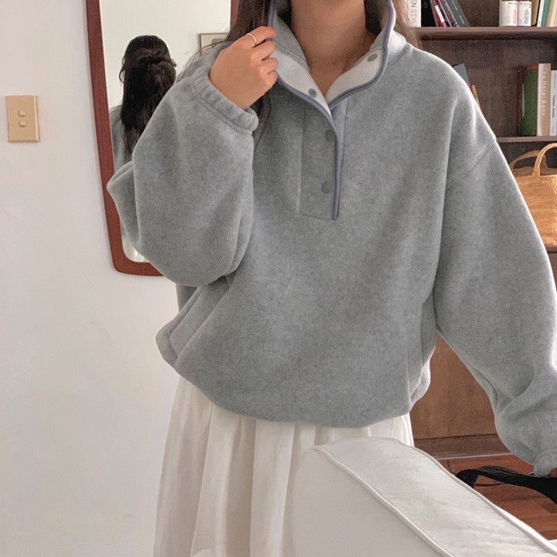 Donna con maglione grigio oversize e gonna bianca in una stanza accogliente. Moda casual autunnale, abbigliamento comodo, stile minimalista.