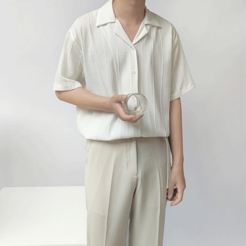 Uomo in camicia bianca e pantaloni beige tiene un bicchiere trasparente. Moda minimalista estiva, abbigliamento casual elegante.