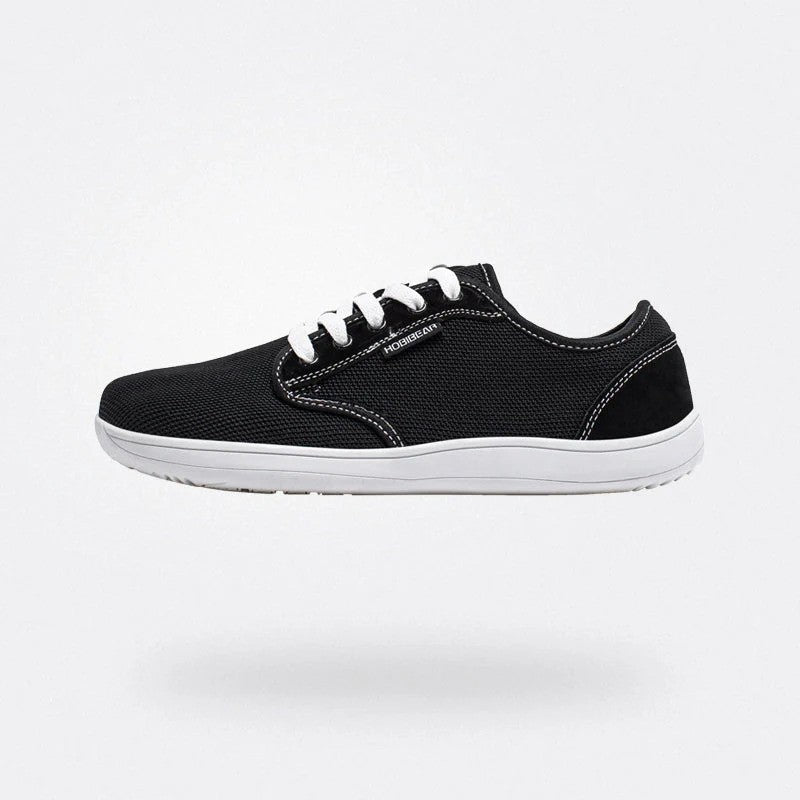 Scarpa da ginnastica nera con suola bianca, design moderno e lacci bianchi, ideale per sport e tempo libero. Comfort e stile casual.