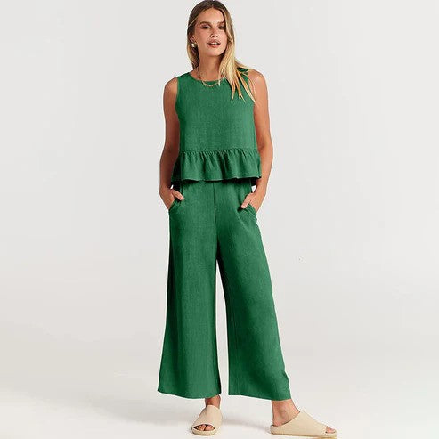 Donna in tuta verde elegante, senza maniche, con pantaloni larghi e sandali beige. Moda estiva, abbigliamento casual chic.