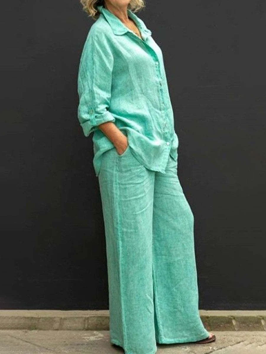 Donna in abbigliamento estivo verde acqua, camicia e pantaloni larghi in lino, moda casual, sfondo nero.