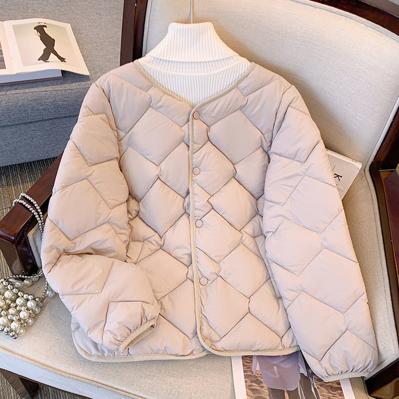 Giacca trapuntata beige su sedia, design a rombi, colletto alto bianco, bottoni frontali. Moda autunno inverno, abbigliamento casual elegante.