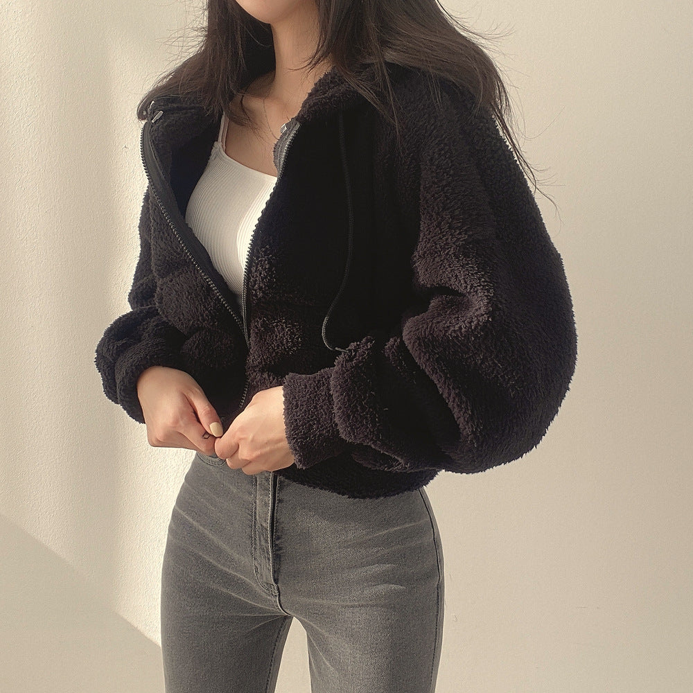 Donna con giacca in pile nero, top bianco e jeans grigi. Moda autunnale, abbigliamento casual, stile confortevole.