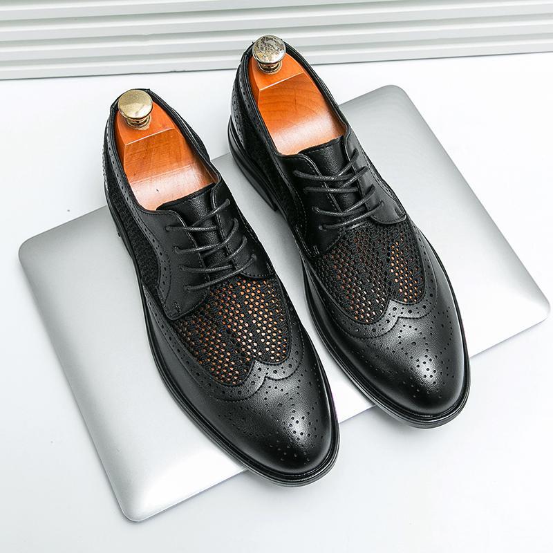 Scarpe eleganti da uomo in pelle nera traforata su laptop, design brogue, lacci, suola in gomma, moda business casual, accessori maschili.