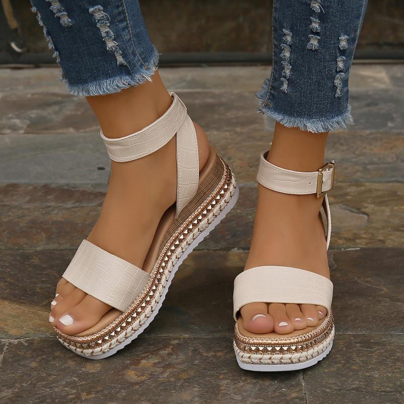 Sandali estivi bianchi con zeppa, cinturino alla caviglia e dettagli intrecciati, indossati con jeans strappati. Scarpe moda donna casual eleganti.