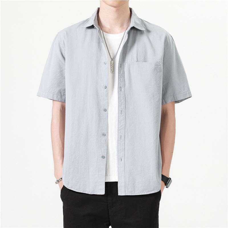 Camicia uomo a maniche corte grigia, stile casual, indossata sopra una maglietta bianca. Moda estiva, abbigliamento maschile elegante e moderno.