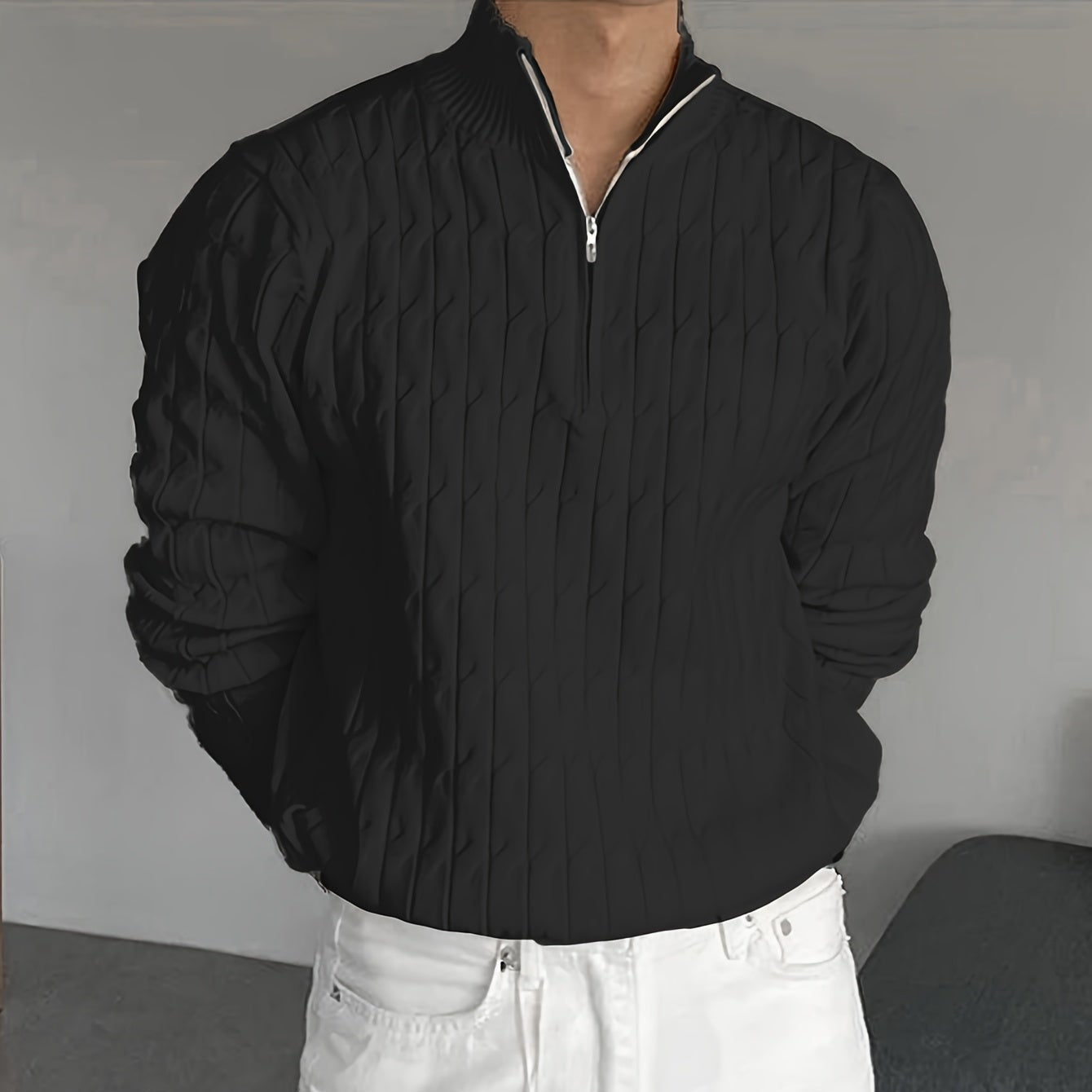 Maglione nero a coste con zip indossato da una persona, abbinato a pantaloni bianchi. Moda casual elegante, abbigliamento autunnale.