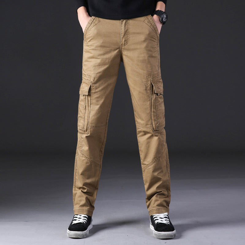 Pantaloni cargo uomo beige, tasche multiple, stile casual, indossati con scarpe sportive nere, sfondo grigio. Moda maschile contemporanea.