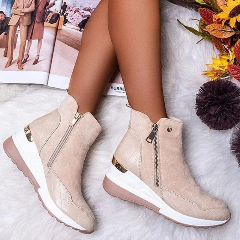 Stivaletti beige con zeppa, cerniera laterale e dettagli dorati su sfondo autunnale. Scarpe moda donna, eleganti e comode per l'autunno.