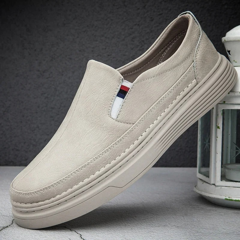 Scarpa slip-on beige da uomo, design casual ed elegante, suola in gomma, dettaglio tricolore, perfetta per look quotidiani e comfort.