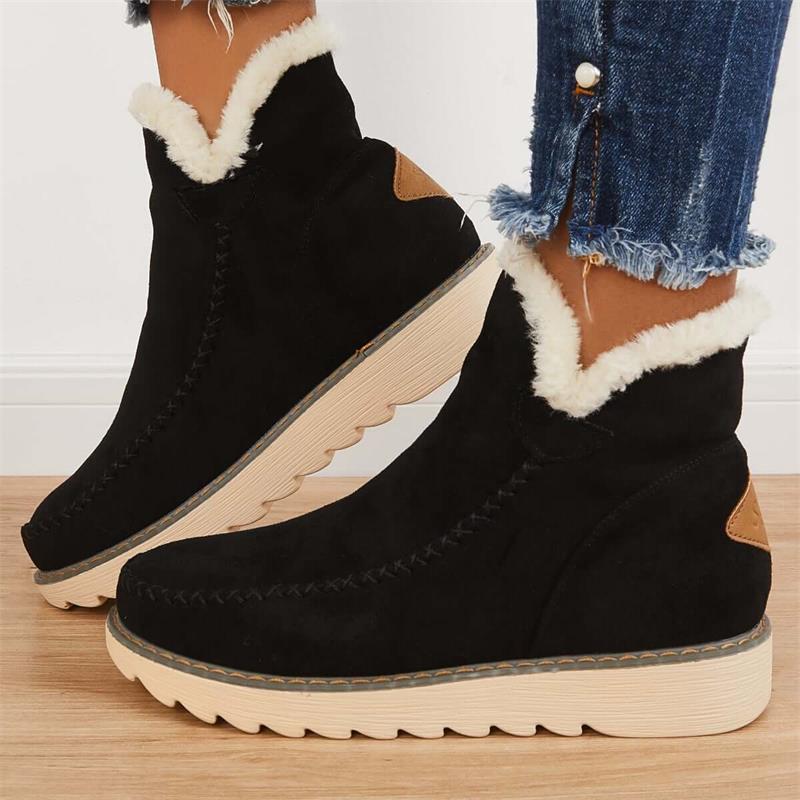 Stivali invernali neri con fodera in pelliccia sintetica, suola in gomma beige, indossati con jeans strappati. Scarpe calde e alla moda per l'inverno.