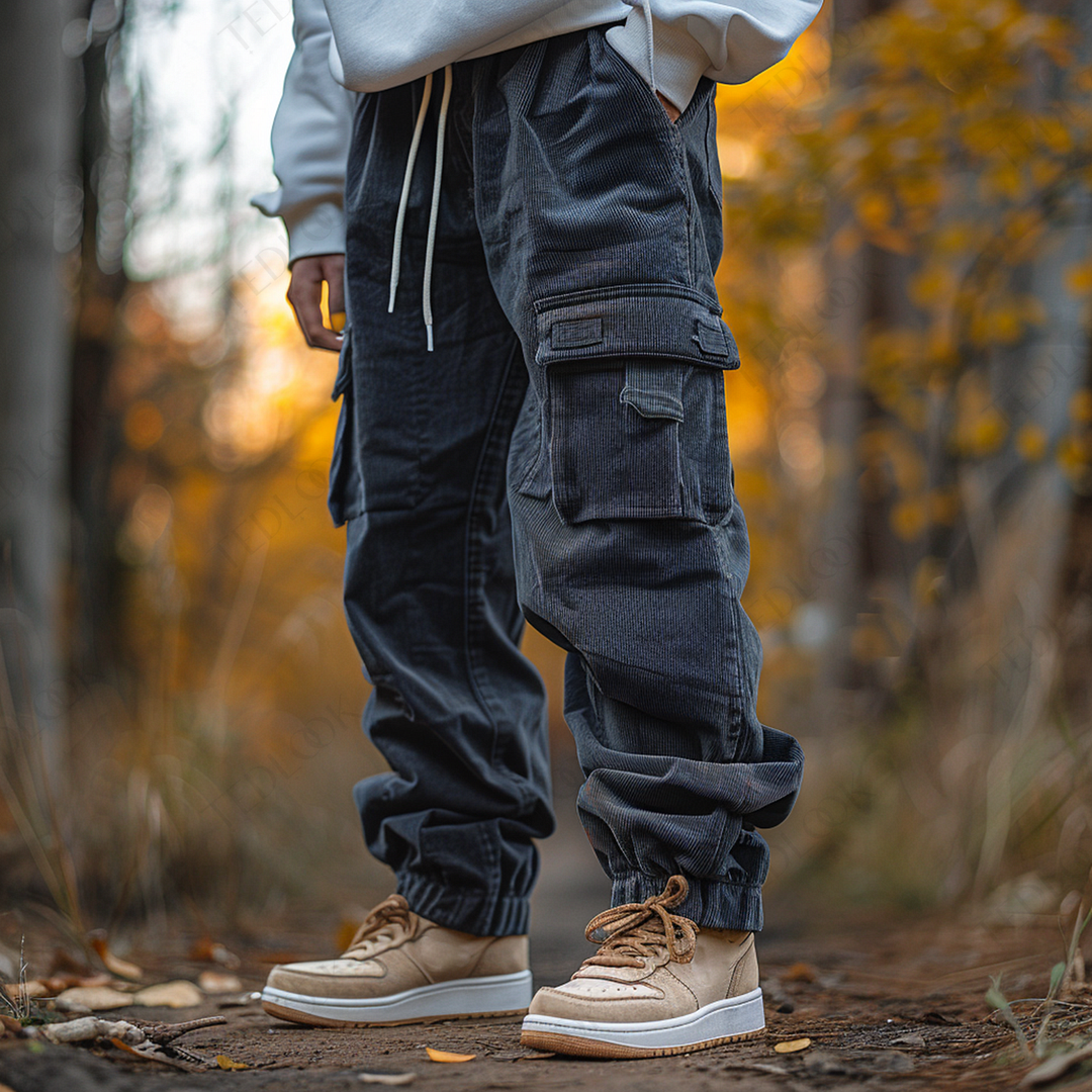 Pantaloni cargo neri in tessuto pesante, indossati con scarpe beige su un sentiero autunnale. Moda casual autunno, abbigliamento outdoor.