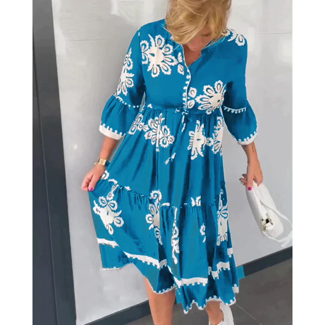 Abito estivo donna blu con motivi floreali bianchi, maniche a tre quarti, lunghezza al ginocchio. Moda casual elegante, accessori bianchi.