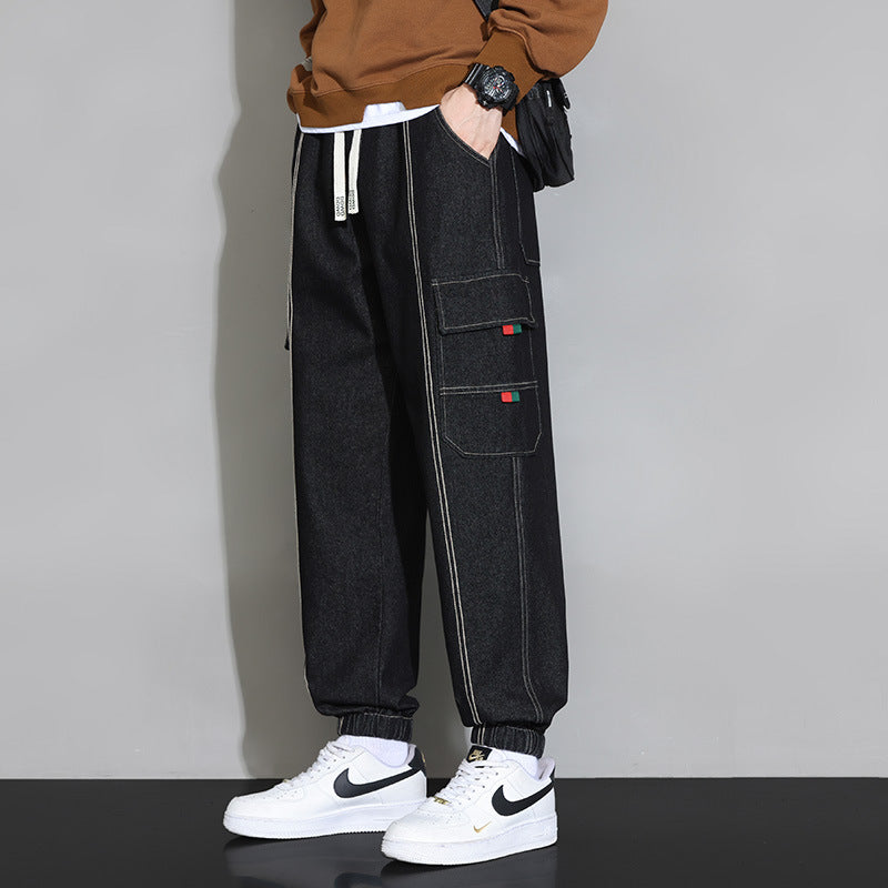 Pantaloni cargo neri da uomo con tasche laterali, abbinati a scarpe da ginnastica bianche Nike. Stile casual e moderno, moda streetwear.