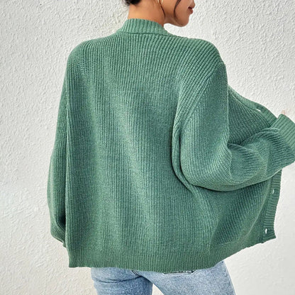 Donna con cardigan verde oversize in maglia, abbinato a jeans chiari. Moda autunnale casual, stile confortevole e trendy.