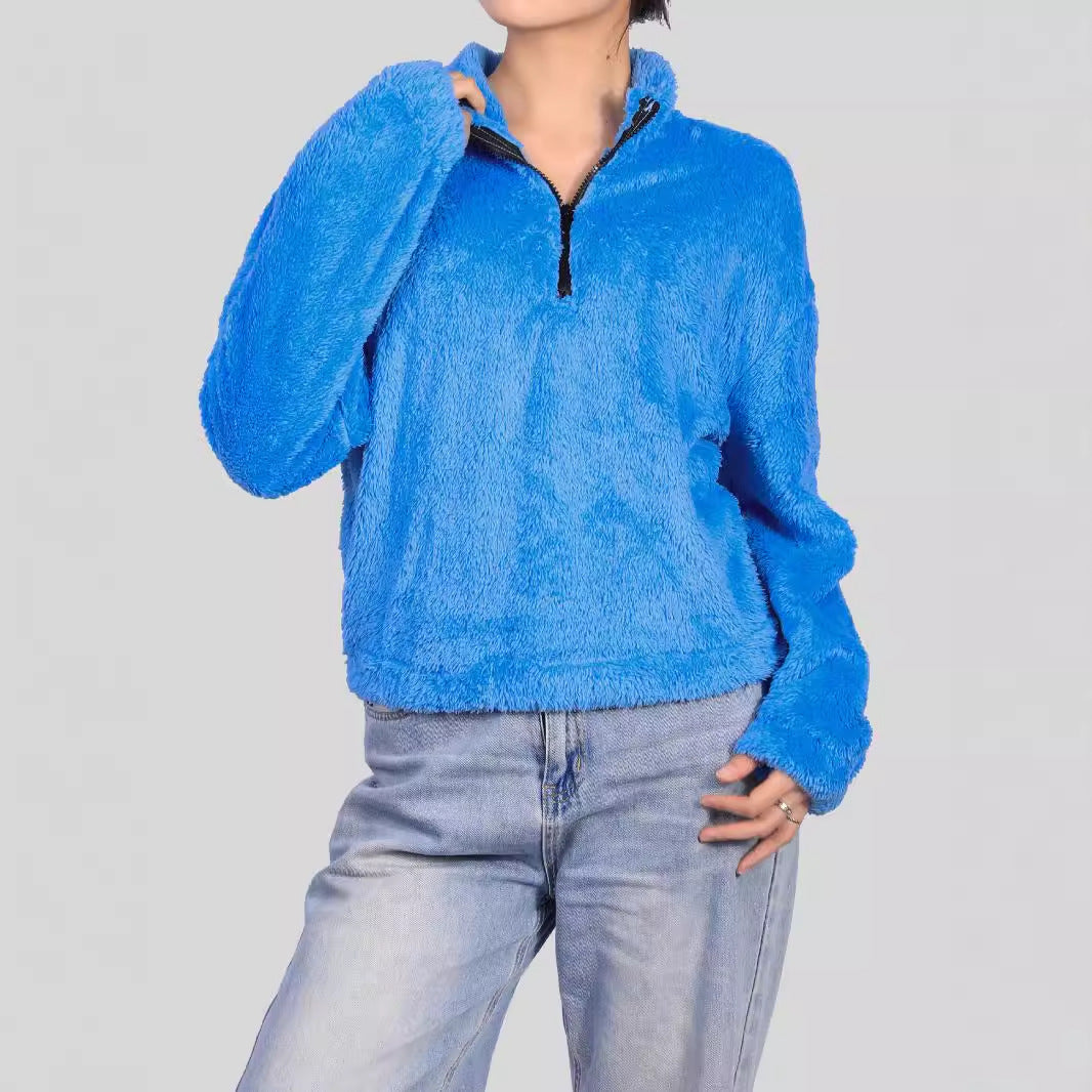 Donna con maglione blu in pile, zip frontale, maniche lunghe, abbinato a jeans chiari. Moda casual, abbigliamento invernale, stile confortevole.