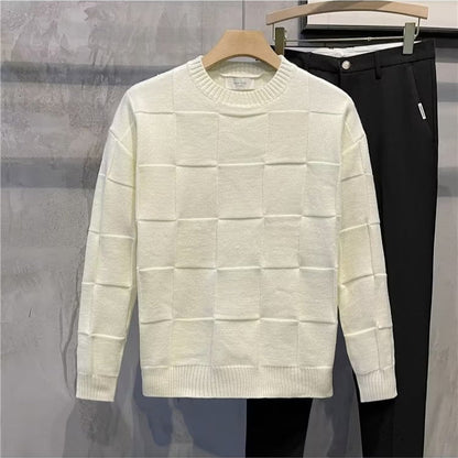 Maglione bianco a quadri in lana su gruccia accanto a pantaloni neri eleganti. Moda autunnale, abbigliamento casual chic, negozio di abbigliamento.